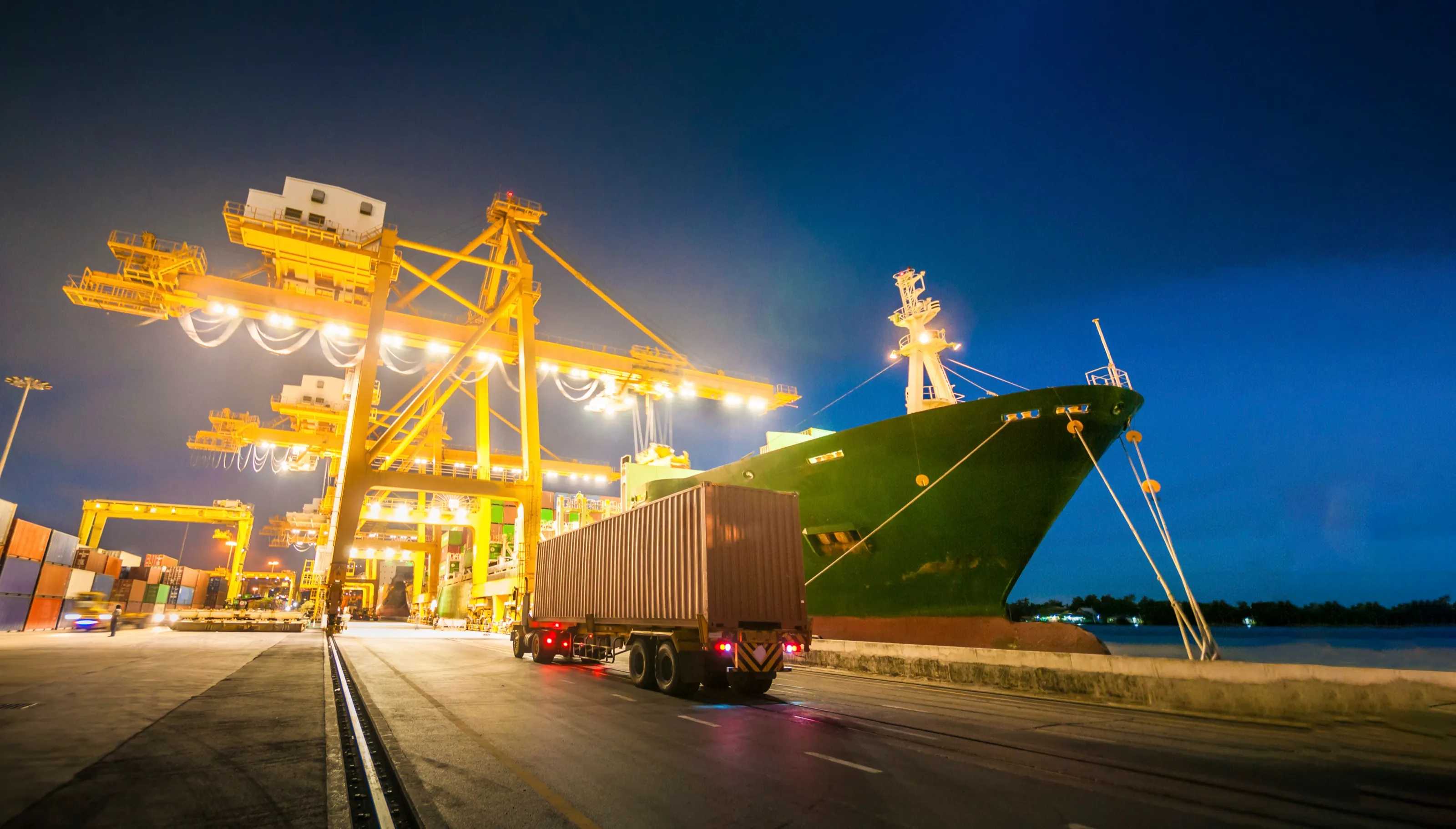Container ship and cranes at a port at dusk